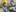 Smiling man holding a tablet talking to another smiling man wearing a hard hat in a warehouse.