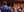 Back of a man in a business suit speaking to a crowd of people at an event.